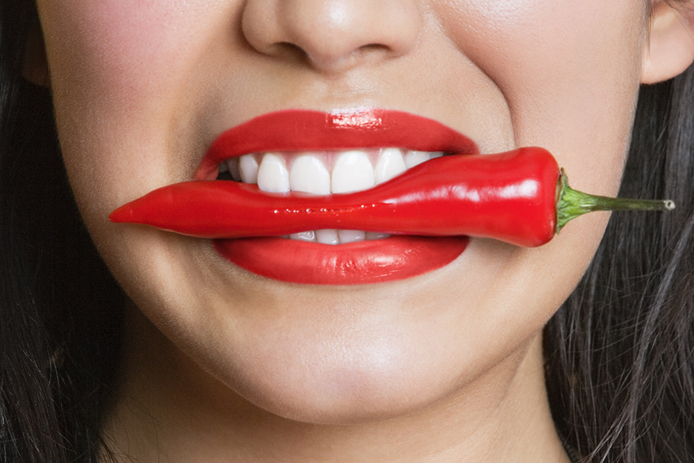 woman biting red pepper